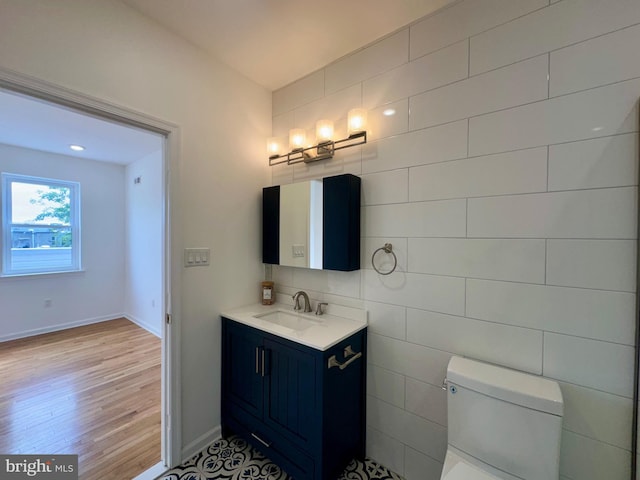 bathroom featuring hardwood / wood-style flooring, vanity, toilet, and tile walls