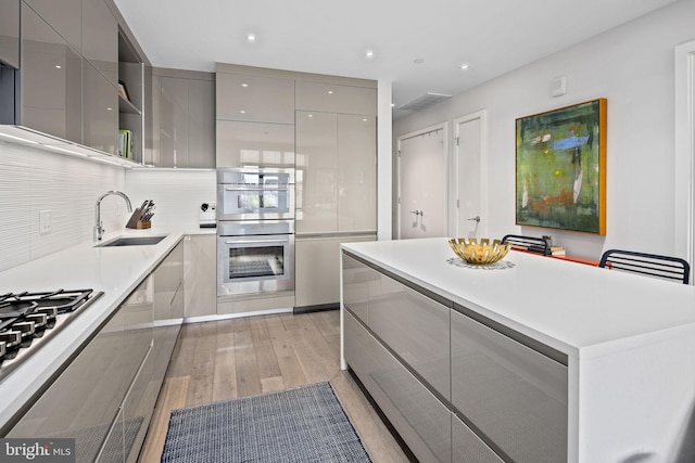 kitchen featuring gray cabinets, light wood-type flooring, sink, and appliances with stainless steel finishes