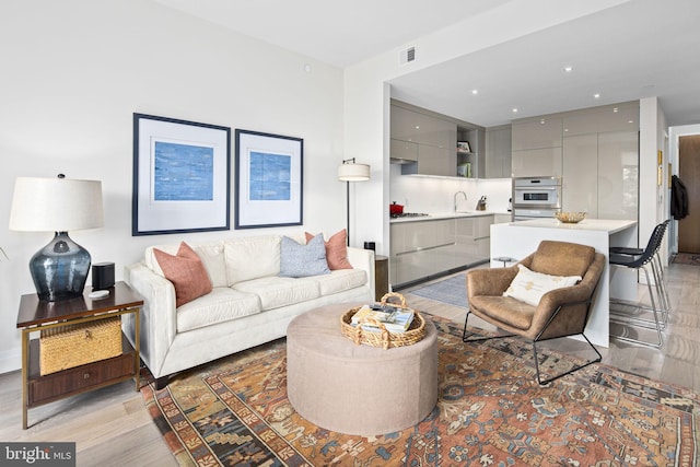 living room with light hardwood / wood-style flooring and sink