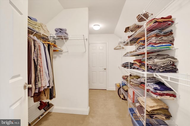 spacious closet with light colored carpet and vaulted ceiling