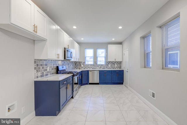 kitchen with blue cabinetry, decorative backsplash, white cabinets, and stainless steel appliances