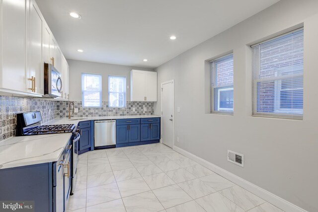 kitchen with blue cabinetry, sink, stainless steel appliances, decorative backsplash, and white cabinets