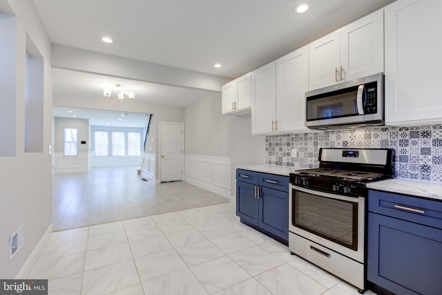 kitchen with backsplash, stainless steel appliances, blue cabinets, a notable chandelier, and white cabinets