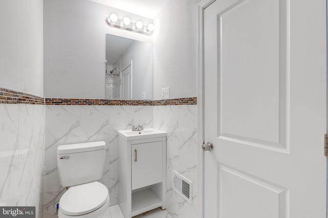 bathroom featuring vanity, toilet, and tile walls