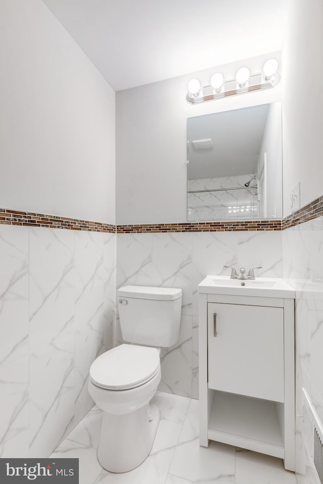 bathroom with vanity, toilet, and tile walls