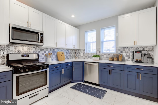 kitchen with tasteful backsplash, stainless steel appliances, sink, blue cabinetry, and white cabinetry