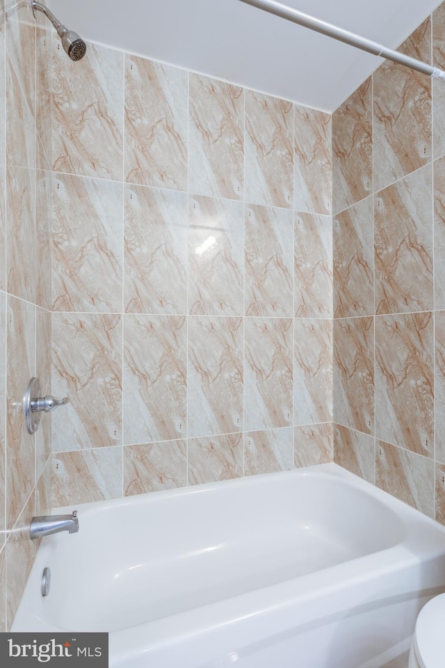 bathroom with tiled shower / bath combo and toilet