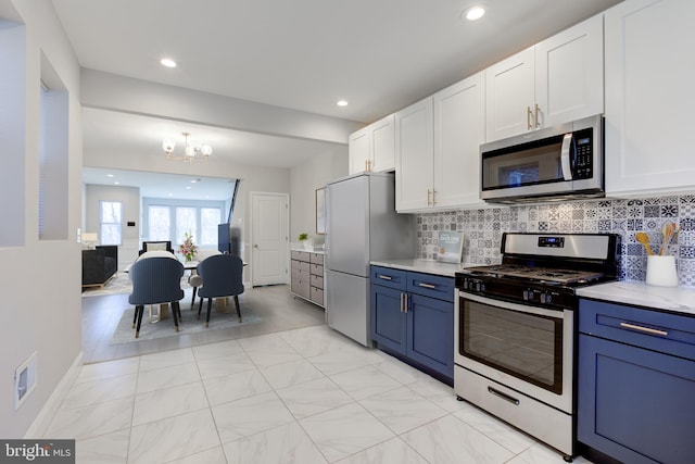 kitchen featuring blue cabinetry, white cabinetry, stainless steel appliances, tasteful backsplash, and a notable chandelier