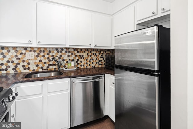 kitchen featuring dark stone countertops, white cabinetry, sink, and stainless steel appliances