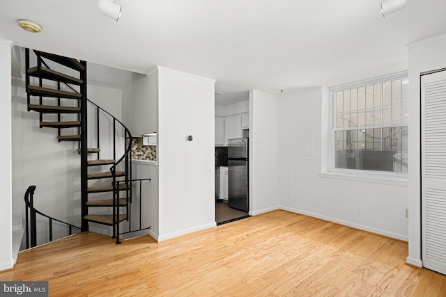 unfurnished living room with light hardwood / wood-style floors and crown molding