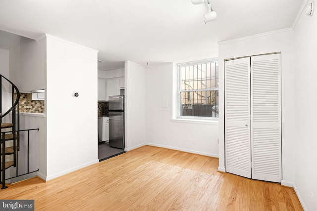 interior space featuring rail lighting, light hardwood / wood-style floors, and crown molding