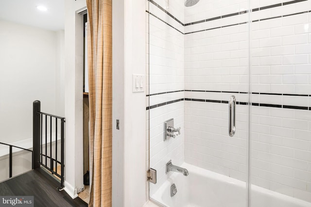 bathroom with hardwood / wood-style floors and bath / shower combo with glass door