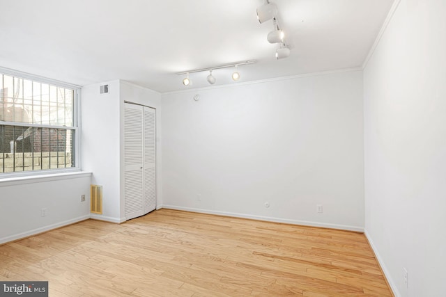 unfurnished bedroom with crown molding, a closet, and light wood-type flooring