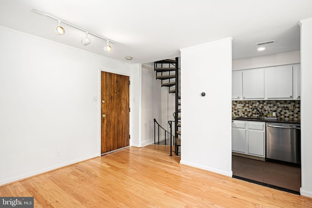 kitchen with dishwasher, light wood-type flooring, tasteful backsplash, and sink