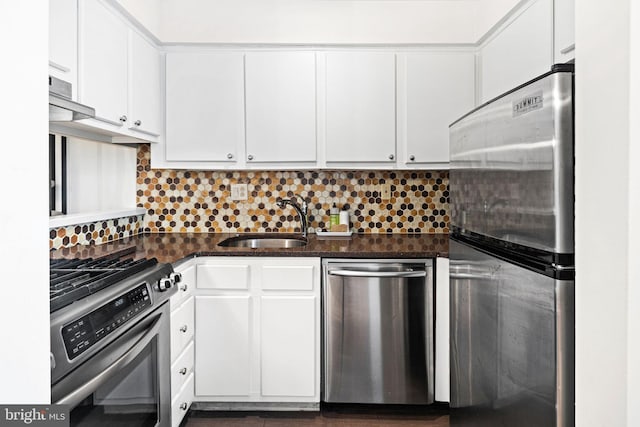 kitchen with sink, stainless steel appliances, backsplash, dark stone counters, and white cabinets