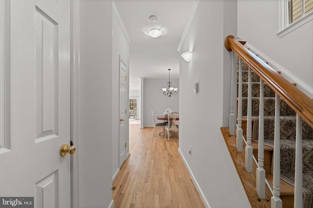 hallway featuring crown molding, a notable chandelier, and light hardwood / wood-style flooring