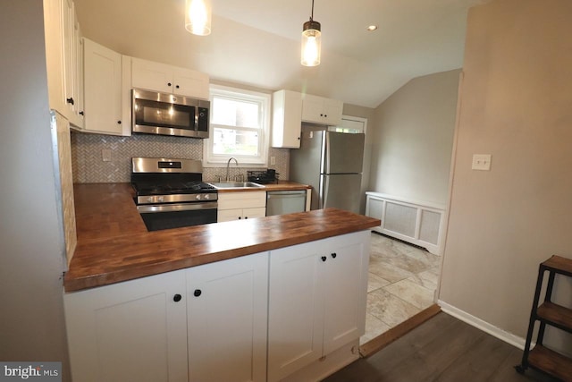 kitchen with white cabinets, appliances with stainless steel finishes, butcher block countertops, and decorative light fixtures