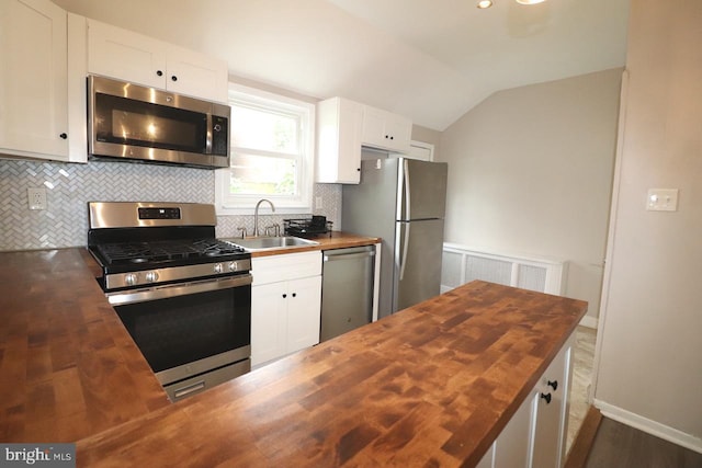 kitchen with butcher block countertops, white cabinetry, sink, and stainless steel appliances