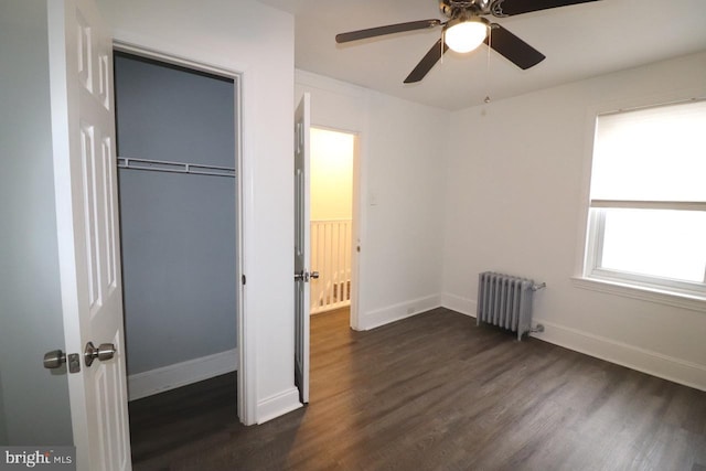 unfurnished bedroom featuring ceiling fan, dark hardwood / wood-style flooring, radiator, and a closet