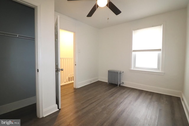 unfurnished bedroom featuring a closet, ceiling fan, radiator heating unit, and dark hardwood / wood-style floors