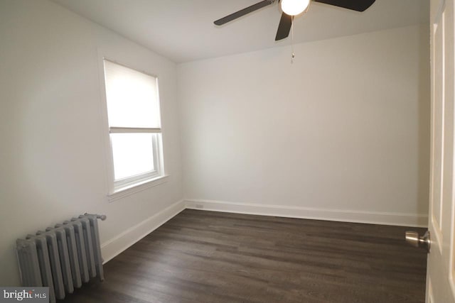 spare room featuring dark hardwood / wood-style floors, radiator, and ceiling fan