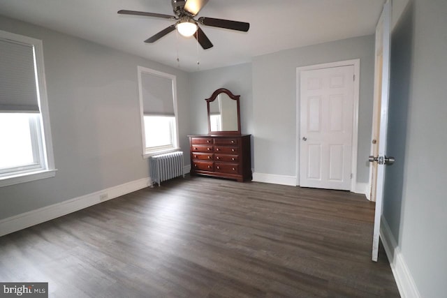 unfurnished bedroom with ceiling fan, dark wood-type flooring, and radiator