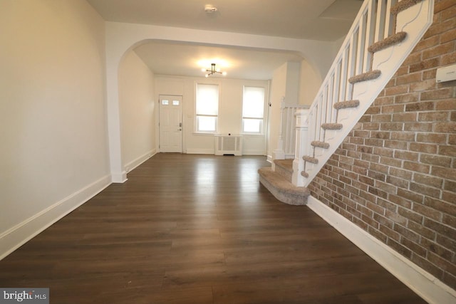 entryway with dark hardwood / wood-style floors, radiator heating unit, and brick wall