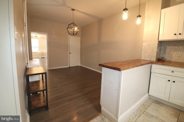 kitchen featuring wooden counters, decorative backsplash, an inviting chandelier, white cabinetry, and hanging light fixtures