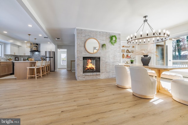 dining space featuring a fireplace, light hardwood / wood-style floors, and an inviting chandelier