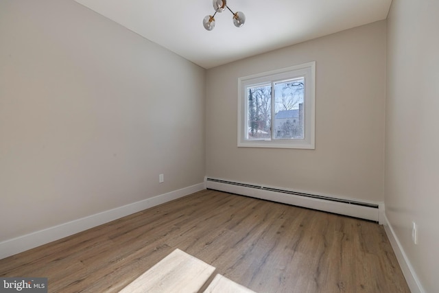 empty room with light hardwood / wood-style floors, an inviting chandelier, and a baseboard heating unit