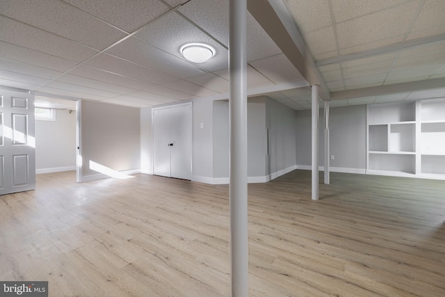 basement with a paneled ceiling and hardwood / wood-style floors