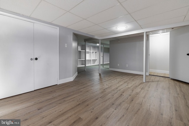 basement featuring a drop ceiling and wood-type flooring