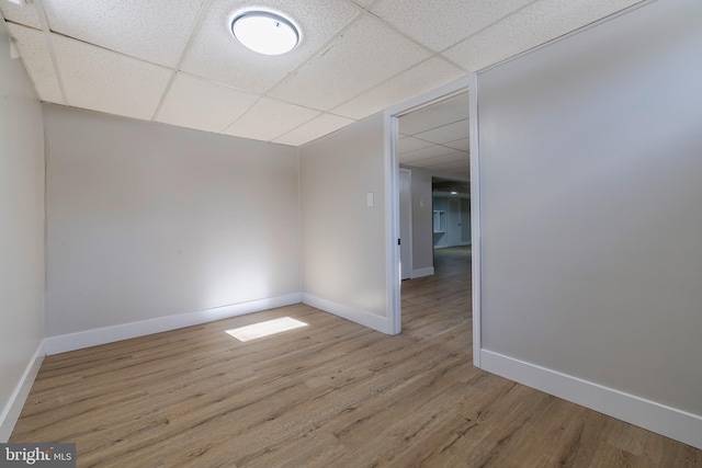 spare room featuring light wood-type flooring and a drop ceiling