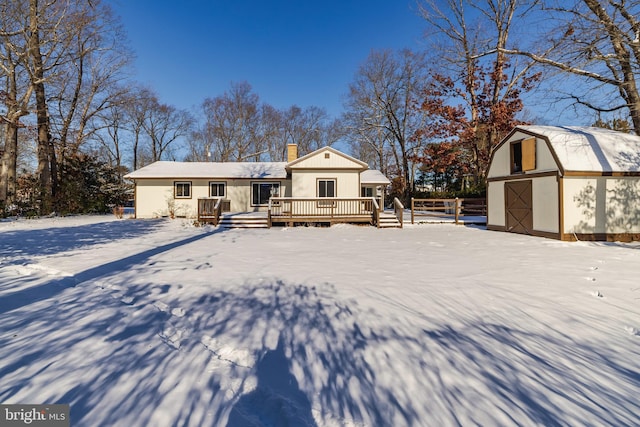 snow covered house with an outbuilding and a wooden deck