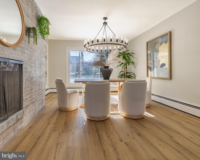 unfurnished dining area featuring hardwood / wood-style flooring, a baseboard heating unit, a fireplace, and an inviting chandelier