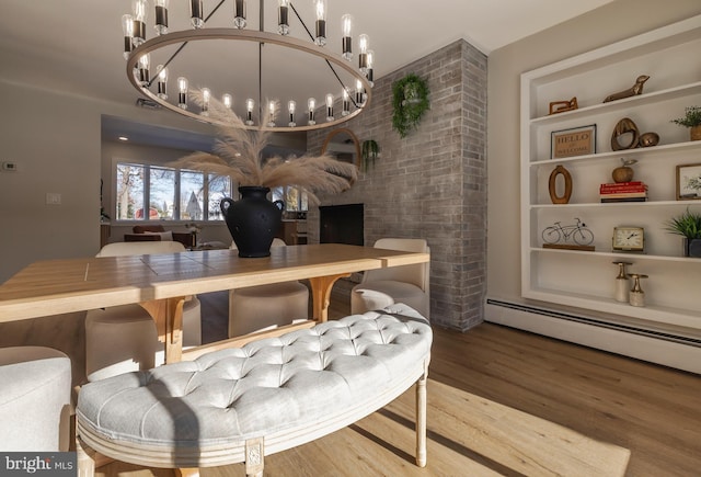 dining room with wood-type flooring, baseboard heating, and an inviting chandelier