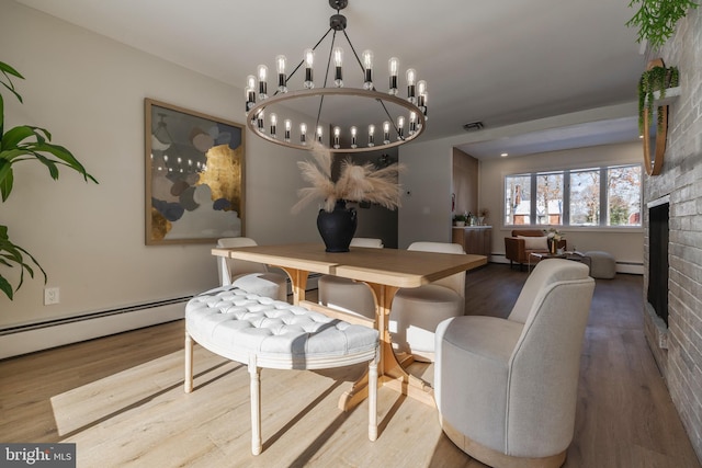 dining space featuring a fireplace, wood-type flooring, and a baseboard heating unit