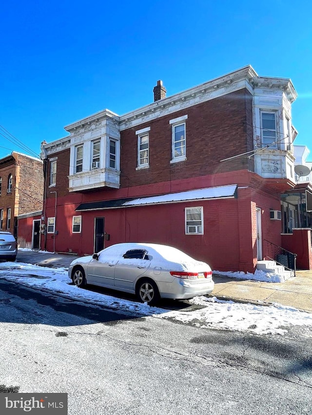 view of front of property featuring a chimney and brick siding