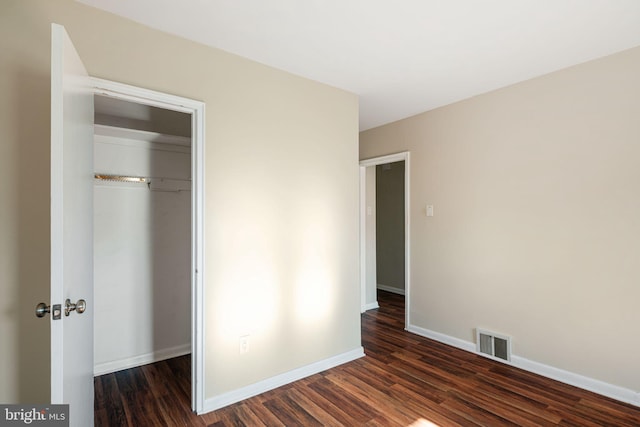 unfurnished bedroom with dark hardwood / wood-style flooring and a closet