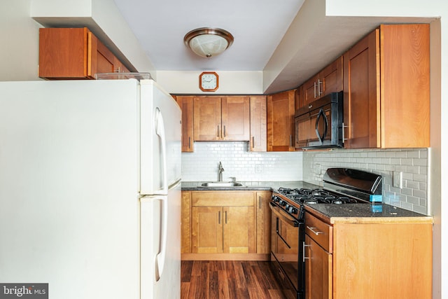 kitchen featuring sink, dark hardwood / wood-style floors, backsplash, dark stone countertops, and black appliances