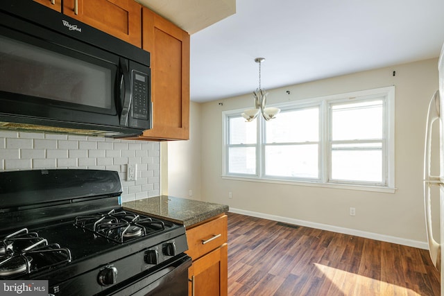 kitchen with dark hardwood / wood-style flooring, a notable chandelier, dark stone countertops, decorative light fixtures, and black appliances