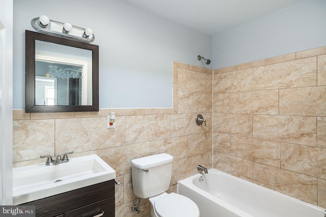 full bathroom featuring vanity, toilet, tiled shower / bath, and tile walls