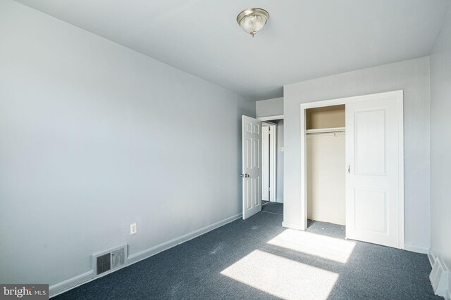 unfurnished bedroom with a closet and dark carpet