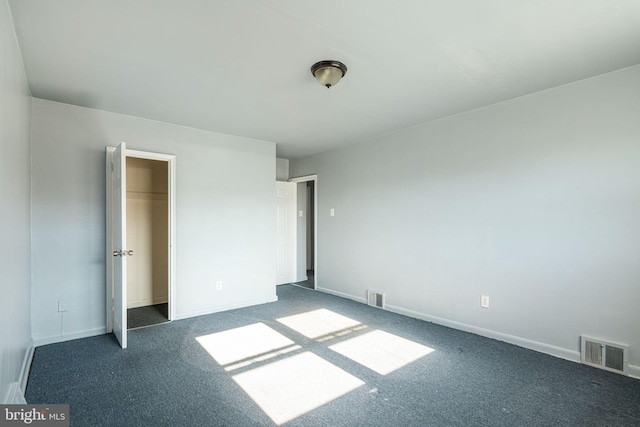 unfurnished bedroom featuring dark carpet and a closet