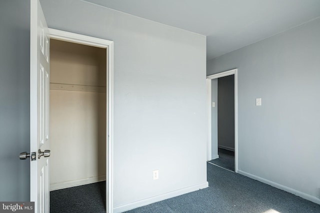 unfurnished bedroom with dark colored carpet and a closet