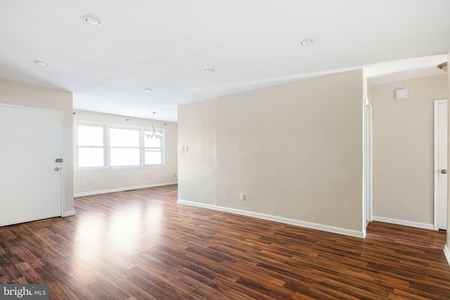 empty room featuring dark hardwood / wood-style floors and an inviting chandelier