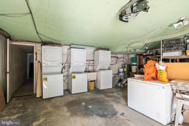 basement featuring water heater, refrigerator, and stacked washer and clothes dryer