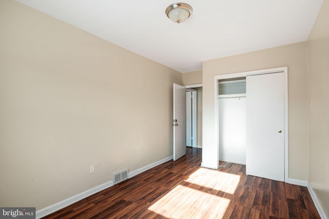 unfurnished bedroom featuring dark wood-type flooring and a closet