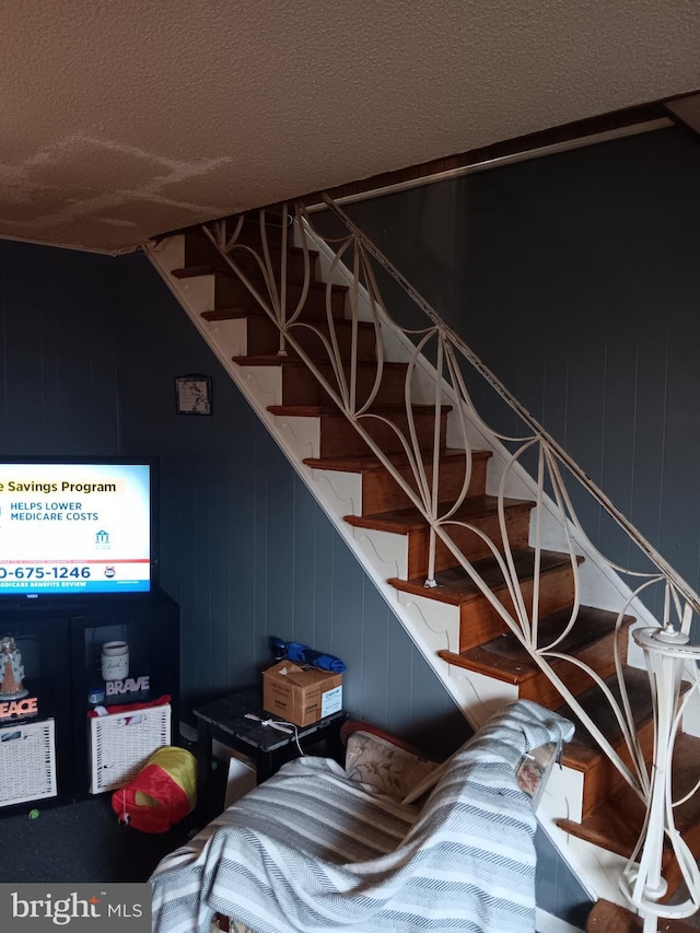 stairway featuring wooden walls and a textured ceiling