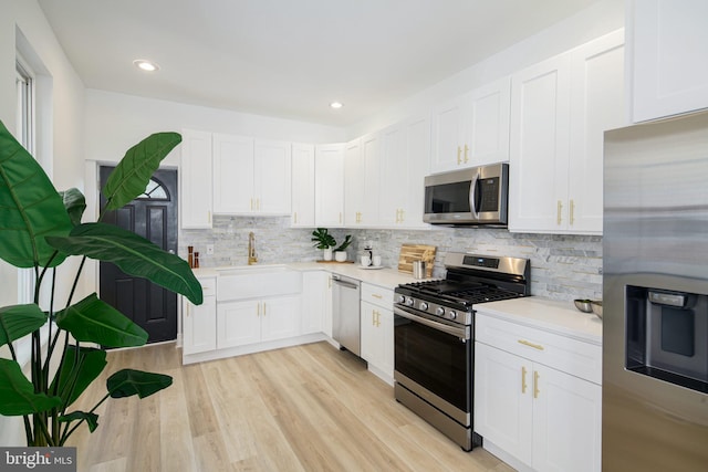 kitchen featuring appliances with stainless steel finishes, light hardwood / wood-style flooring, white cabinetry, and sink